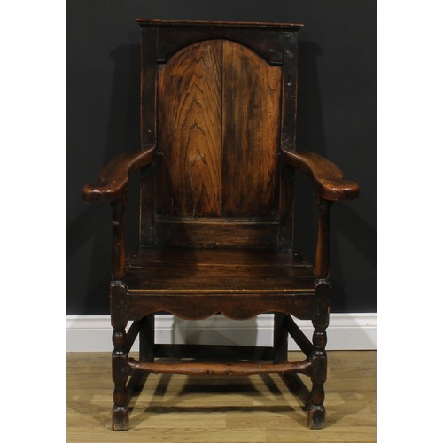 2174 - An 18th century oak and elm panel back armchair, rectangular back, shaped arms, plank seat, shaped a... 