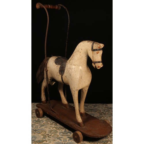 104 - A late 19th century child's push along Horse on wheels, the carved wooden Horse painted white with r... 