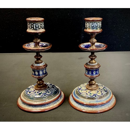 2 - A near pair of Doulton Lambeth brass and earthenware candlesticks, relief decorated with scrolling f... 