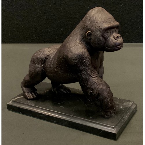 25 - A bronzed metal sculpture of a gorilla, rectangular stepped marble base, 18cm high, 20cm long.
