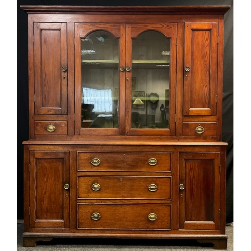 34 - A Victorian Pitch Pine dresser, the top with out-swept cornice over a pair of glazed doors enclosing... 