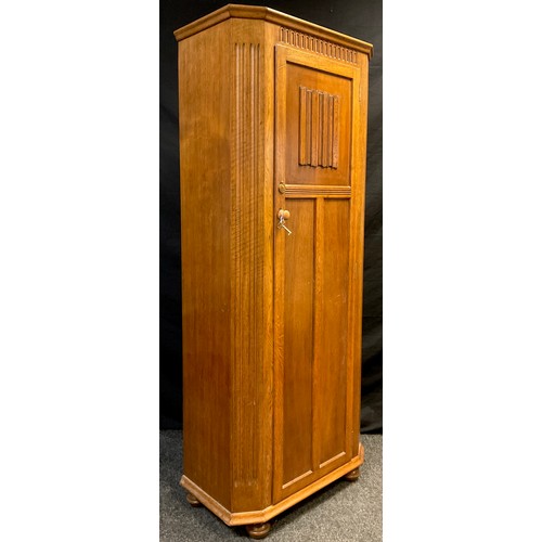 128 - A mid 20th century oak hall robe, canted shaped front, single tall door with carved linen-fold panel... 