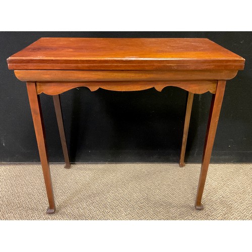 140A - An early 20th century mahogany games table, fold over leather lined top, shaped apron, tapering legs... 