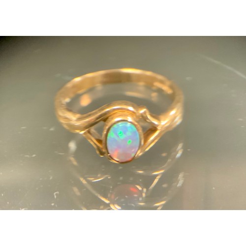 572 - A black opal cabochon ring, approx 0.25ct, with strong green blue and violet colour play, open shoul... 