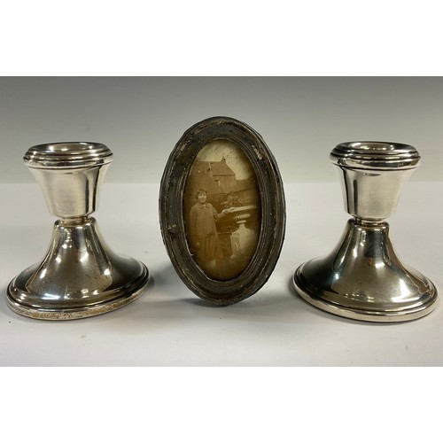 25 - A pair of Elizabeth II silver boudoir candlesticks, Birmingham 1957; a George V silver oval miniatur... 