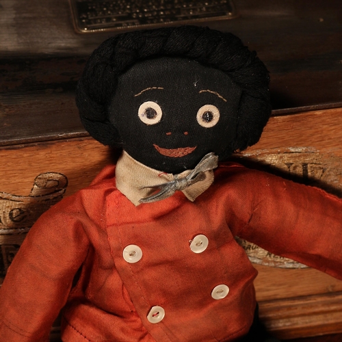 138 - Folk Art - an early 20th century stuffed cloth black doll, the fabric head applied with black and wh... 