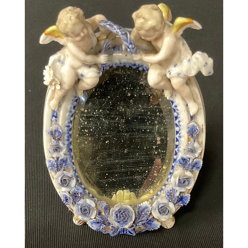 605 - A Continental oval mirror, decorated with cherubs and roses