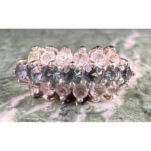 646 - A gold coloured metal cluster dress ring, set with a row of blue coloured stones flanked by two row ... 