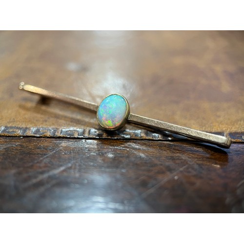 651 - An opal and gold coloured metal bar brooch, the single oval cabochon stone centered on a plain recta... 