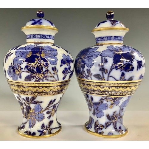 665 - A pair of Wedgwood inverted baluster flow blue urnular vases and covers, printed with foliate stems,... 