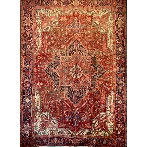 250 - A Persian Heriz carpet, central geometric floral medallion within red ground, surrounded by triple l... 