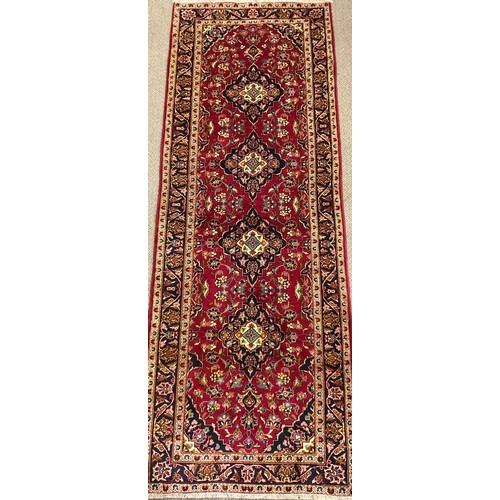 279 - A Central Persian Kashan runner carpet, hand-knotted in rich red, blue, and deep indigo, with highli... 