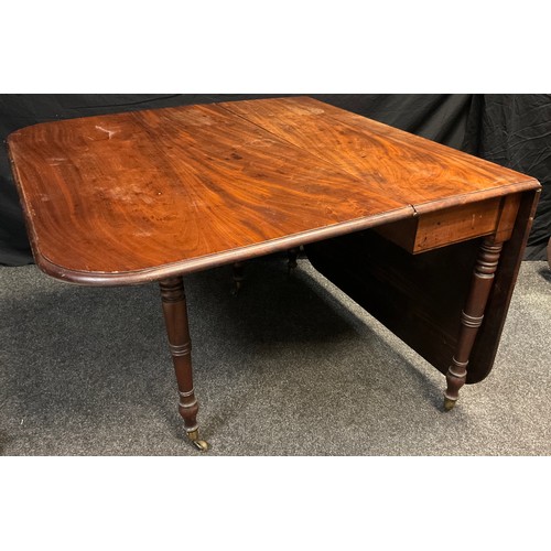 311 - A George III mahogany drop-leaf dining table, rounded rectangular top, turned legs, brass casters, 7... 