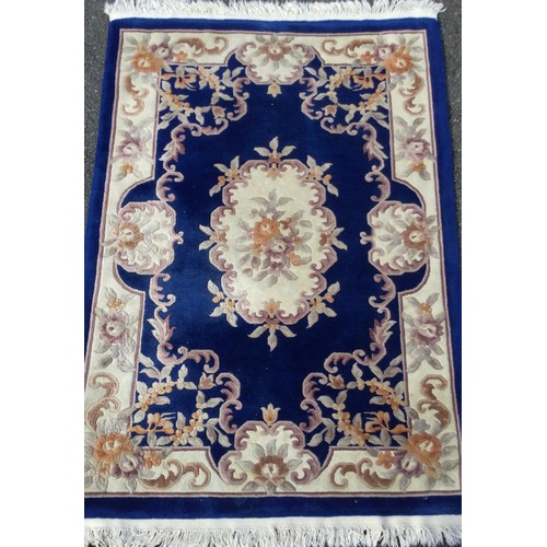 315 - A Chinese deep pile woollen rug / carpet, in deep blue, pink, and cream, 187cm x 126cm.