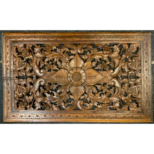 61 - A carved wooden rectangular plaque, pierced floral centre within scrolling surround, dotted boarder,... 