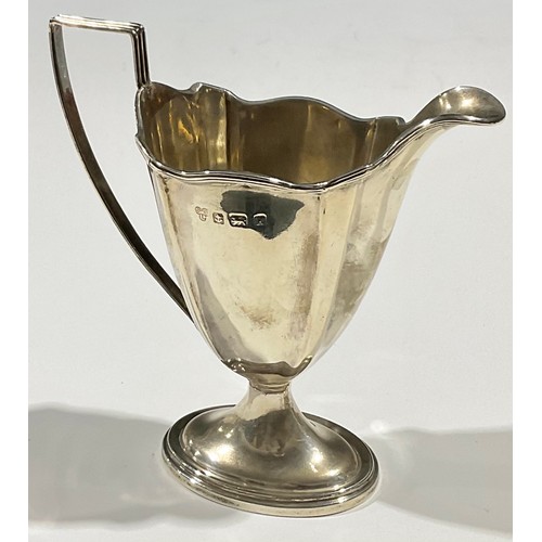 51 - An Edwardian silver pedestal helmet shaped cream jug, angular reeded handle, stepped oval base, 12cm... 
