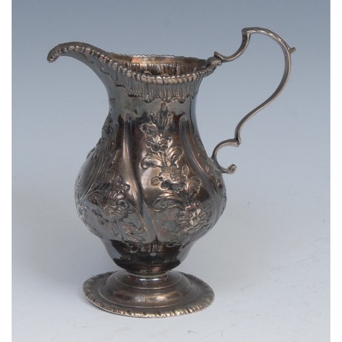 65 - An 18th century silver baluster cream jug, wrythen fluted and chased with flowers and foliage, gadro... 