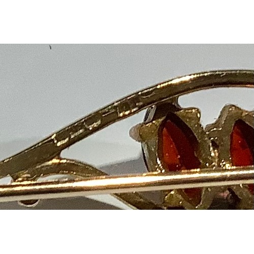 674 - A 9ct gold bar brooch, set with three faceted oval garnets, 4.75cm wide, marked 375, 3.4g