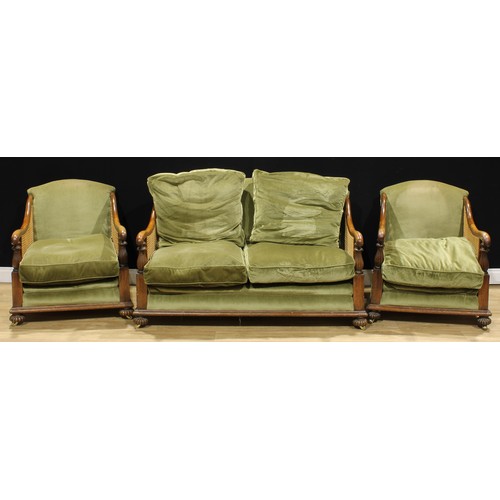 115A - An early 20th century oak three-piece bergère drawing room suite, comprising a sofa and a pair of ar... 