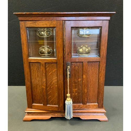 42 - An Edwardian oak smokers cabinet, two door front enclosing fitted interior with four drawers above t... 