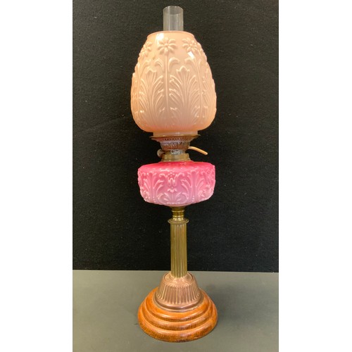 58 - A Victorian oil lamp, pink milk glass reservoir, copper column, floral shade, wooden foot, 67cm high... 
