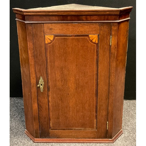 84 - A George III oak corner cupboard, wall-mounted, canted front, inlay to door, enclosing two tiers of ... 