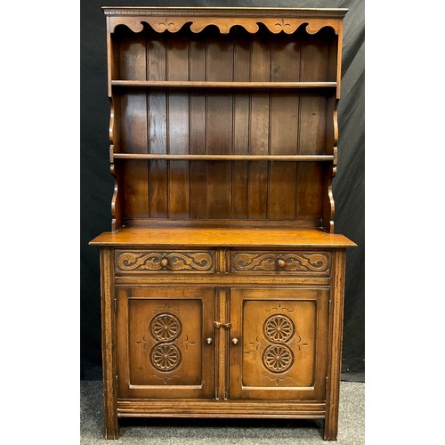 102 - A Titchmarsh and Goodwin style narrow oak dresser, two tiers of shelving to the plate-rack top, abov... 