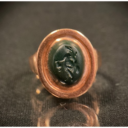 441 - A 19th century intaglio seal ring, carved as a walking figure, unmarked rose metal shank, 5.6g gross