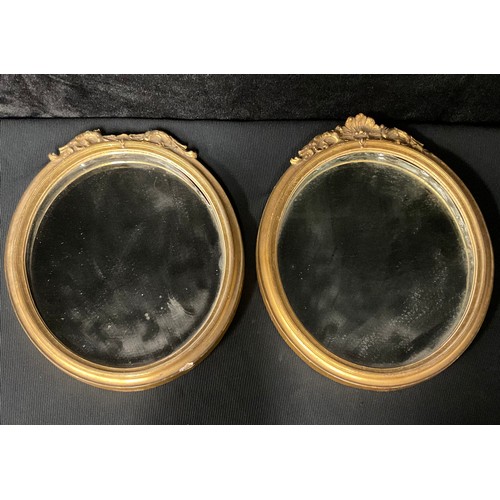 409 - A pair of oval gilt mirrors, the cornice a palmette flanked by acanthus leaves (2)