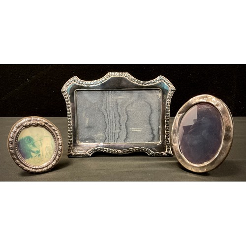 411 - An Edwardian style shaped top silver photograph frame, London 1988,  two others smaller oval (3)