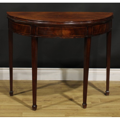 1308 - A George III mahogany demilune card table, hinged top with moulded edge enclosing a baize lined play... 