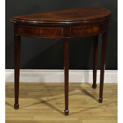 1308 - A George III mahogany demilune card table, hinged top with moulded edge enclosing a baize lined play... 