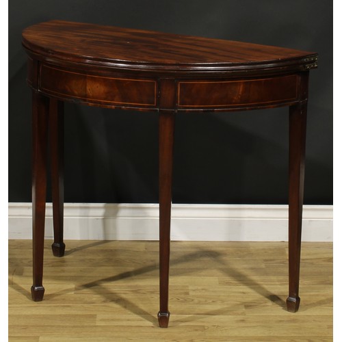 1308 - A George III mahogany demilune card table, hinged top with moulded edge enclosing a baize lined play... 