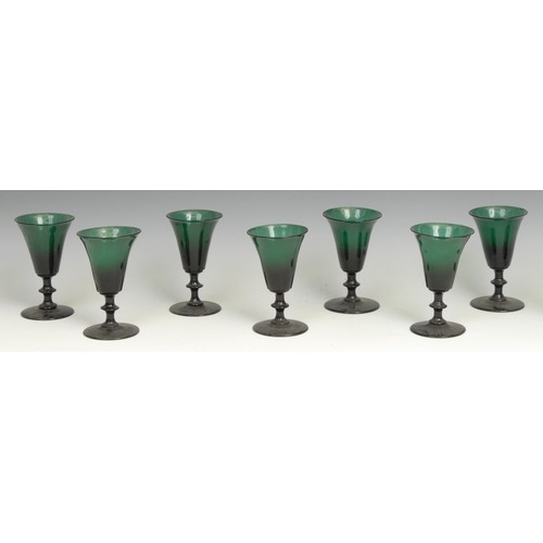 327 - A set of eight mid 19th century green glass conical drinking glasses, flared rims, knopped stems, po... 