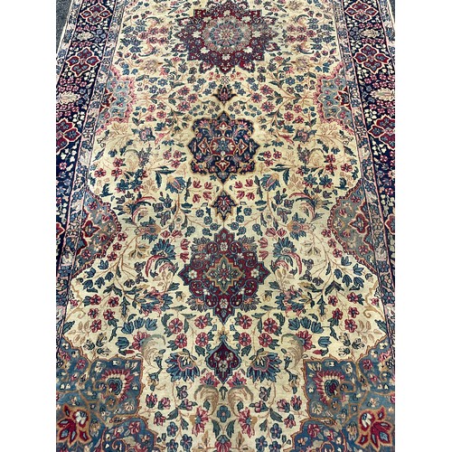 2111 - A large Persian Kerman woollen rug or carpet, stylised flowers and geometric motifs, in tones of red... 