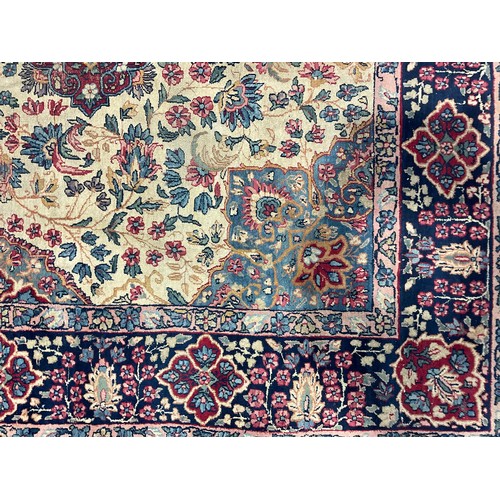 2111 - A large Persian Kerman woollen rug or carpet, stylised flowers and geometric motifs, in tones of red... 