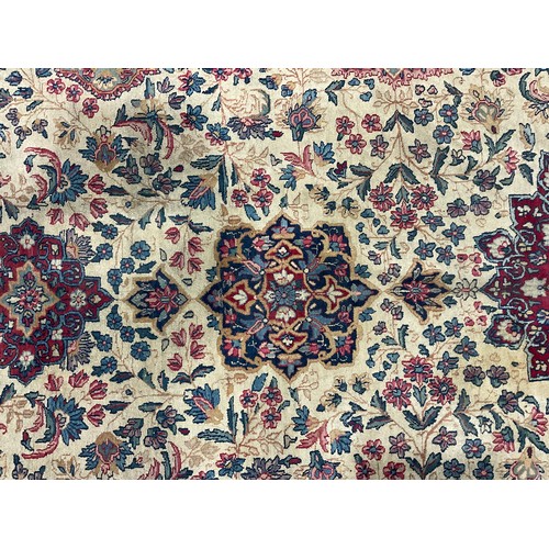 2111 - A large Persian Kerman woollen rug or carpet, stylised flowers and geometric motifs, in tones of red... 