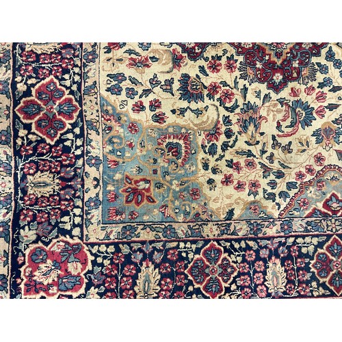 2111 - A large Persian Kerman woollen rug or carpet, stylised flowers and geometric motifs, in tones of red... 