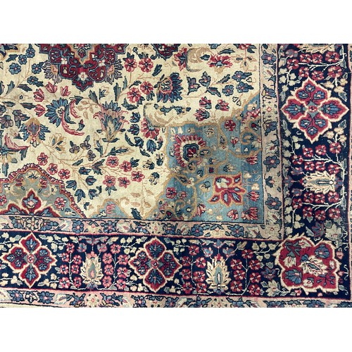 2111 - A large Persian Kerman woollen rug or carpet, stylised flowers and geometric motifs, in tones of red... 