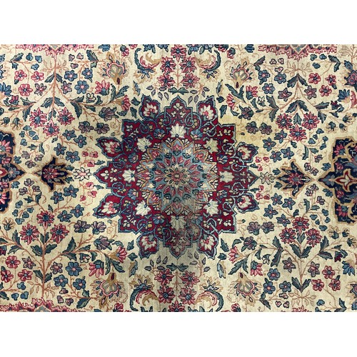 2111 - A large Persian Kerman woollen rug or carpet, stylised flowers and geometric motifs, in tones of red... 