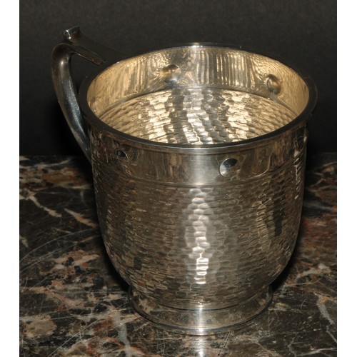 607 - A George V silver cup, in the Arts and Crafts manner, planished with plain border decorated with cir... 