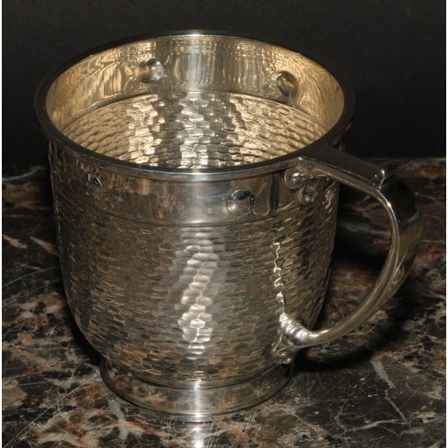 607 - A George V silver cup, in the Arts and Crafts manner, planished with plain border decorated with cir... 