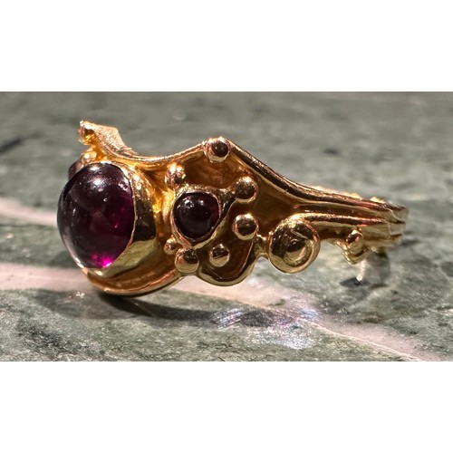 927 - An 18ct gold garnet ring, set with three oval and circular cabochon red garnets, shaped scrolling cr... 