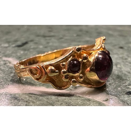 927 - An 18ct gold garnet ring, set with three oval and circular cabochon red garnets, shaped scrolling cr... 