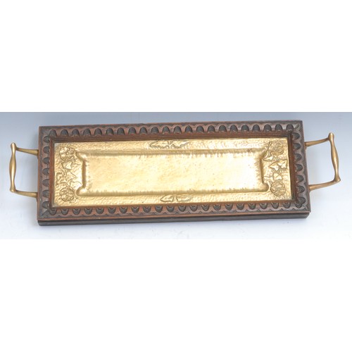 2206 - An Arts and Crafts oak and brass rectangular two-handled serving tray, the planished field chased wi... 