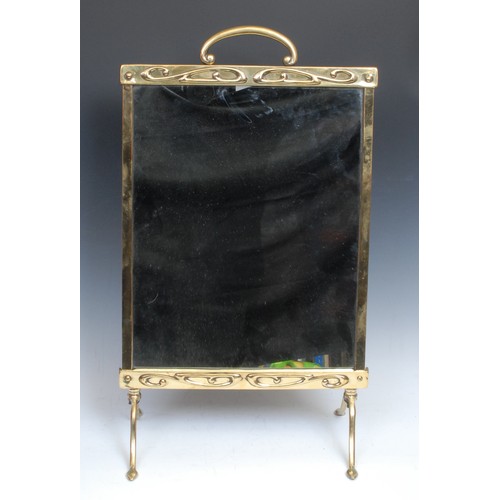 1551 - An Art Nouveau brass fire screen, arched handle, mirrored banner, the frieze and apron embossed with... 