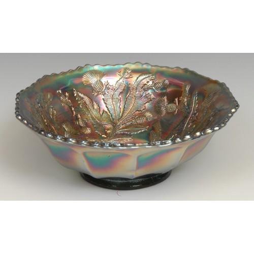 67 - A carnival amethyst glass shaped circular bowl, moulded in low relief with a peacock and leafy folia... 