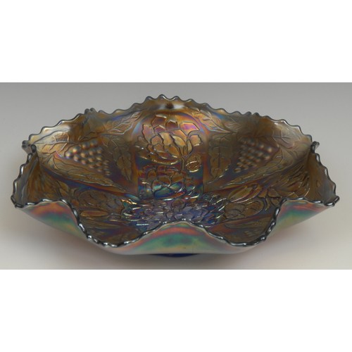 67 - A carnival amethyst glass shaped circular bowl, moulded in low relief with a peacock and leafy folia... 