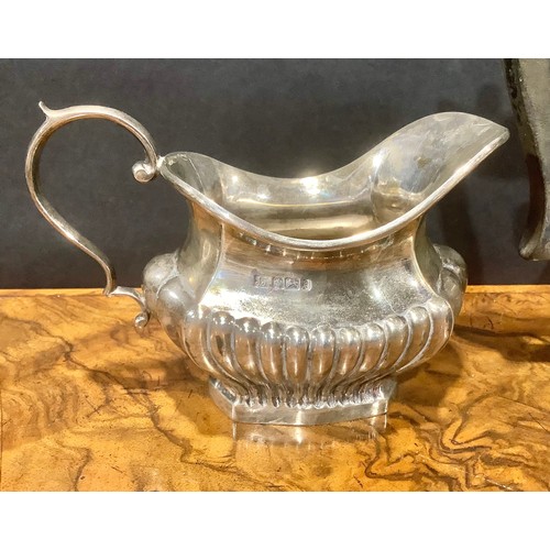 776 - An Edwardian silver half fluted three piece tea service, comprising teapot, sugar basin and cream ju... 