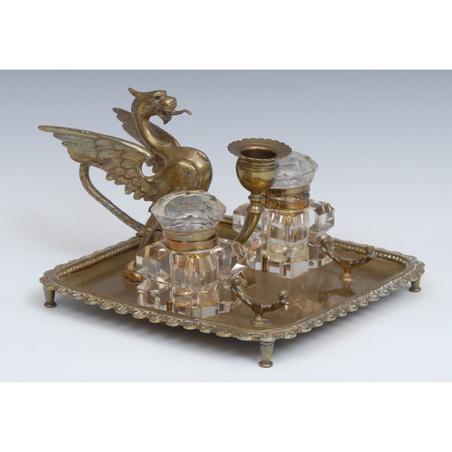 1264 - A 19th century brass inkstand, the handle cast as a wyvern, the square cut glass wells centred by a ... 